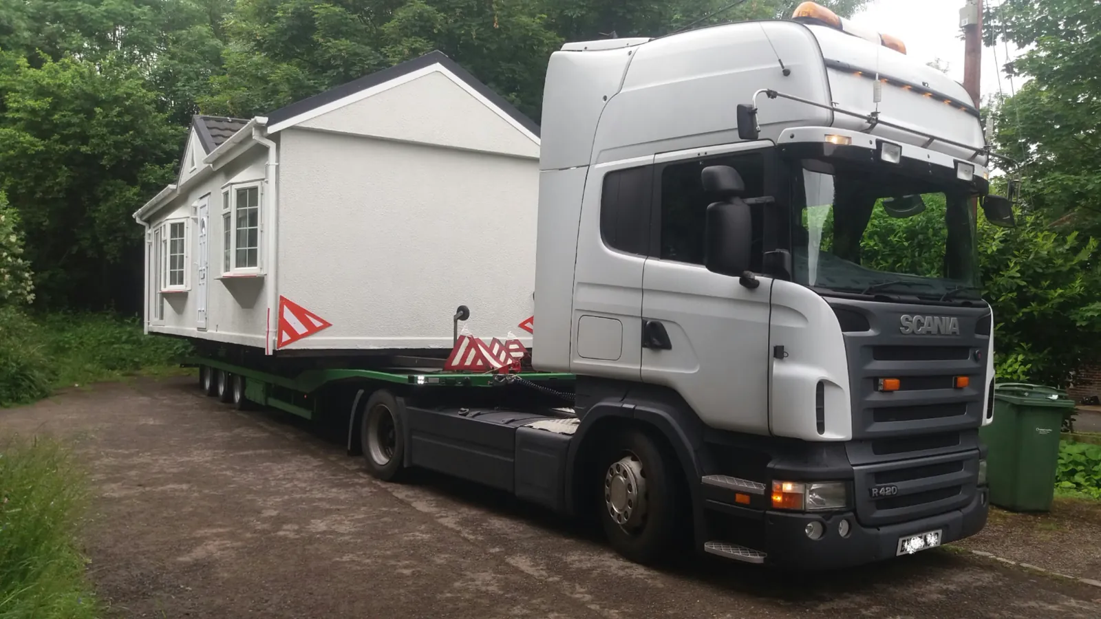 A Scania lorry carrying a white chalet-style unit